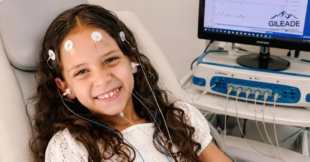 Criança realizando exame de Potencial Evocado Auditivo em clínica neurológica para avaliação das vias auditivas e processamento dos sons pelo cérebro.